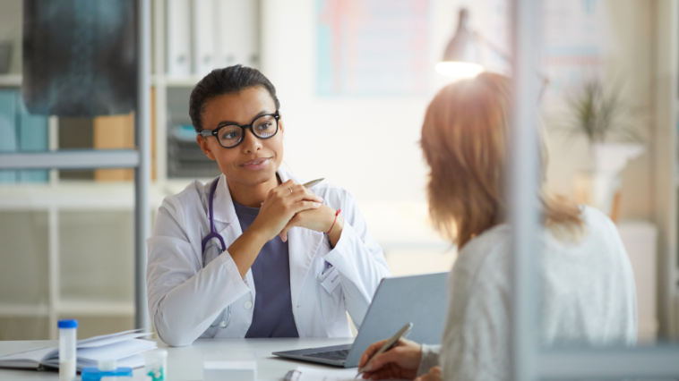 Doctor sitting at a desk speaking with another person